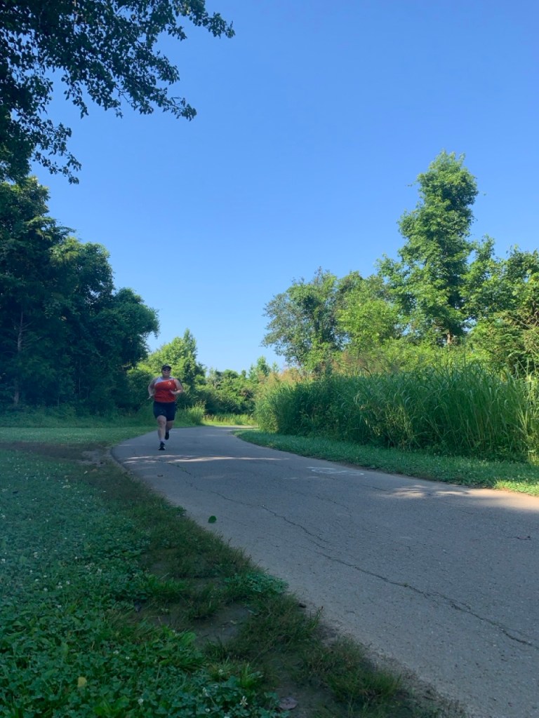 Vanessa Junkin running on a paved path with greenery on both sides.