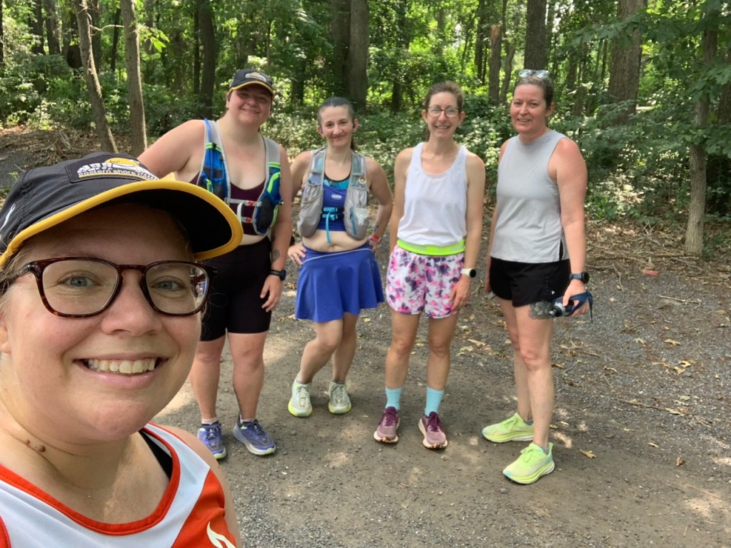Five female runners in a selfie with the woods behind them. 