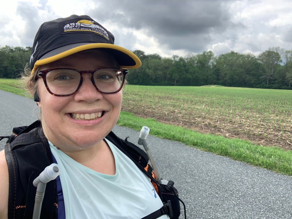 Selfie of sweaty female runner by farm field. 