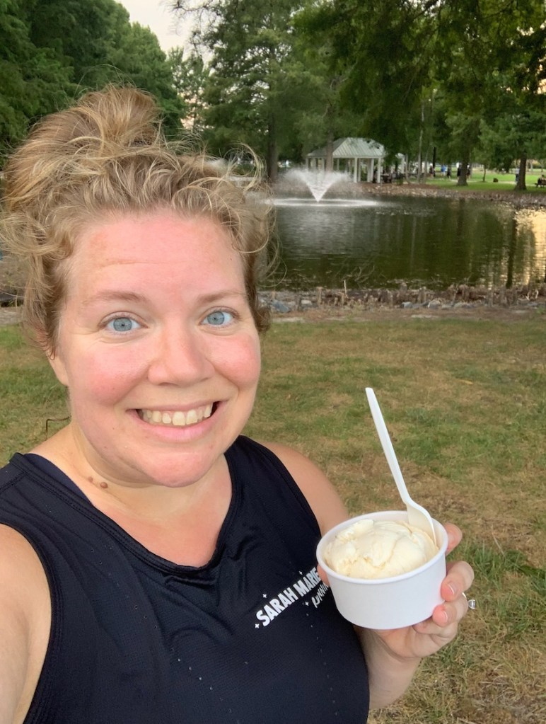 Selfie of Vanessa Junkin holding a cup of ice cream with a fountain in the background.