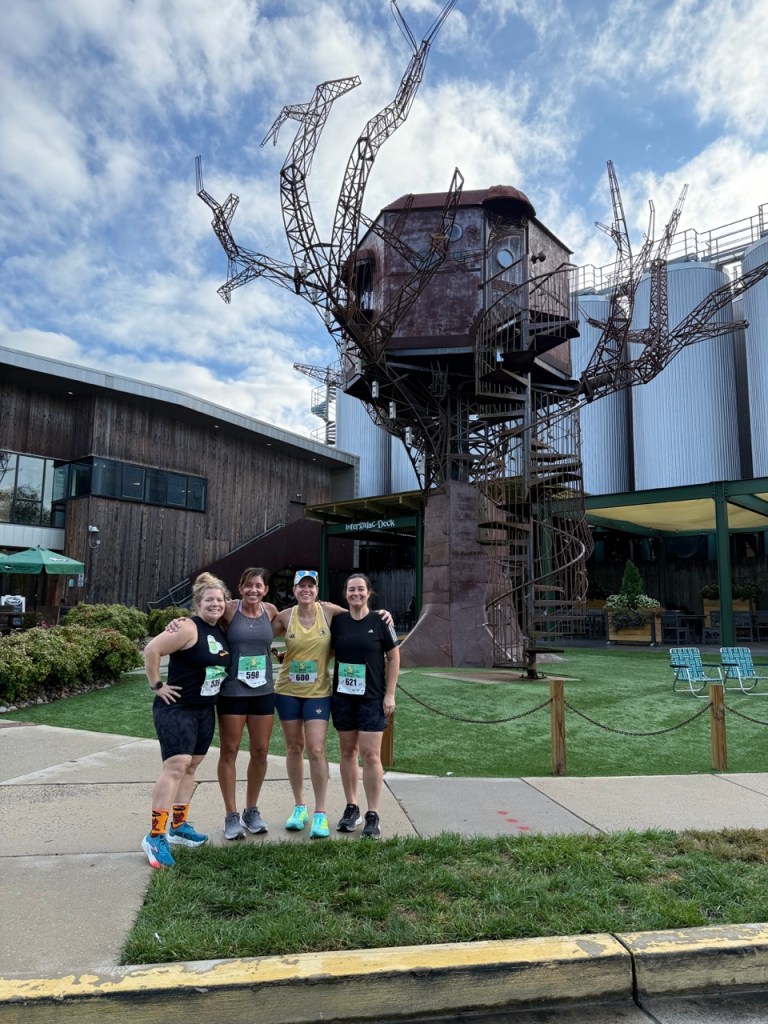 Four runners posing for a photo with the Steampunk Treehouse in the background.
