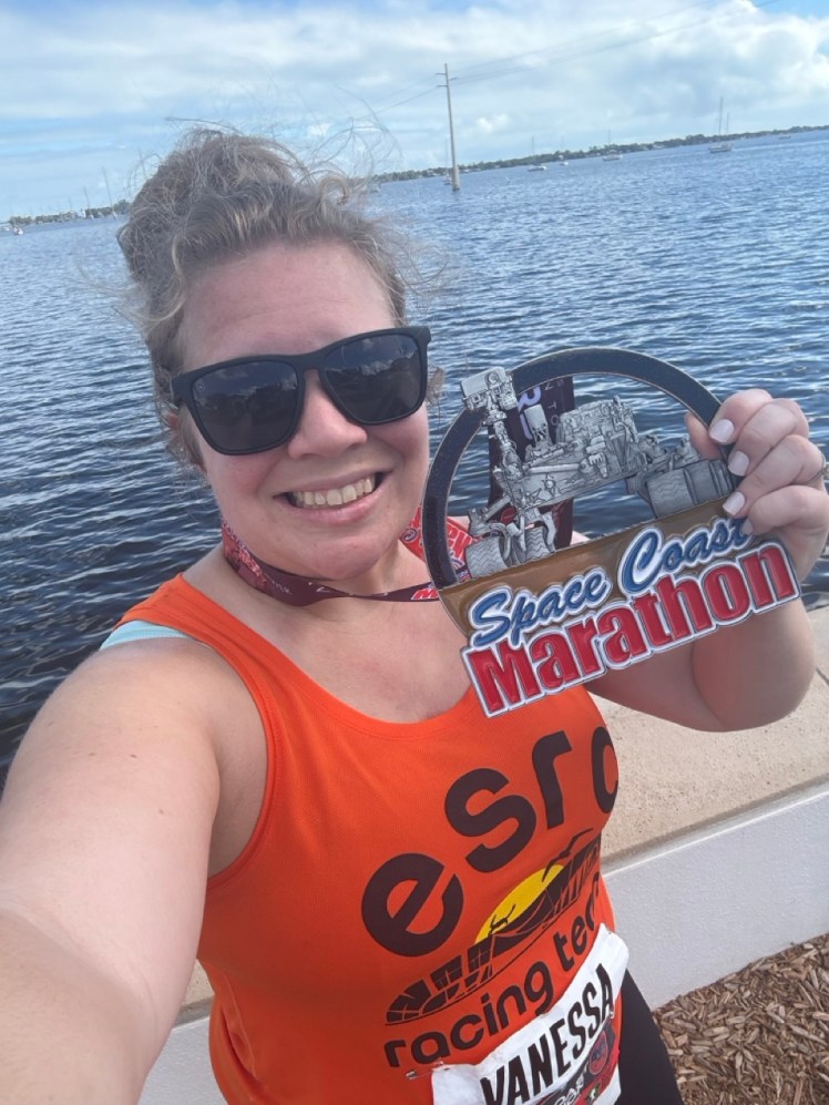 Selfie of Vanessa holding a huge Space Coast Marathon medal
