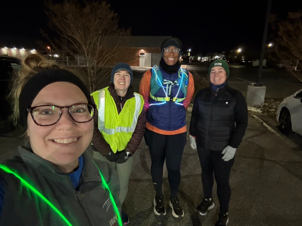 Four runners posing for a photo in the dark. 