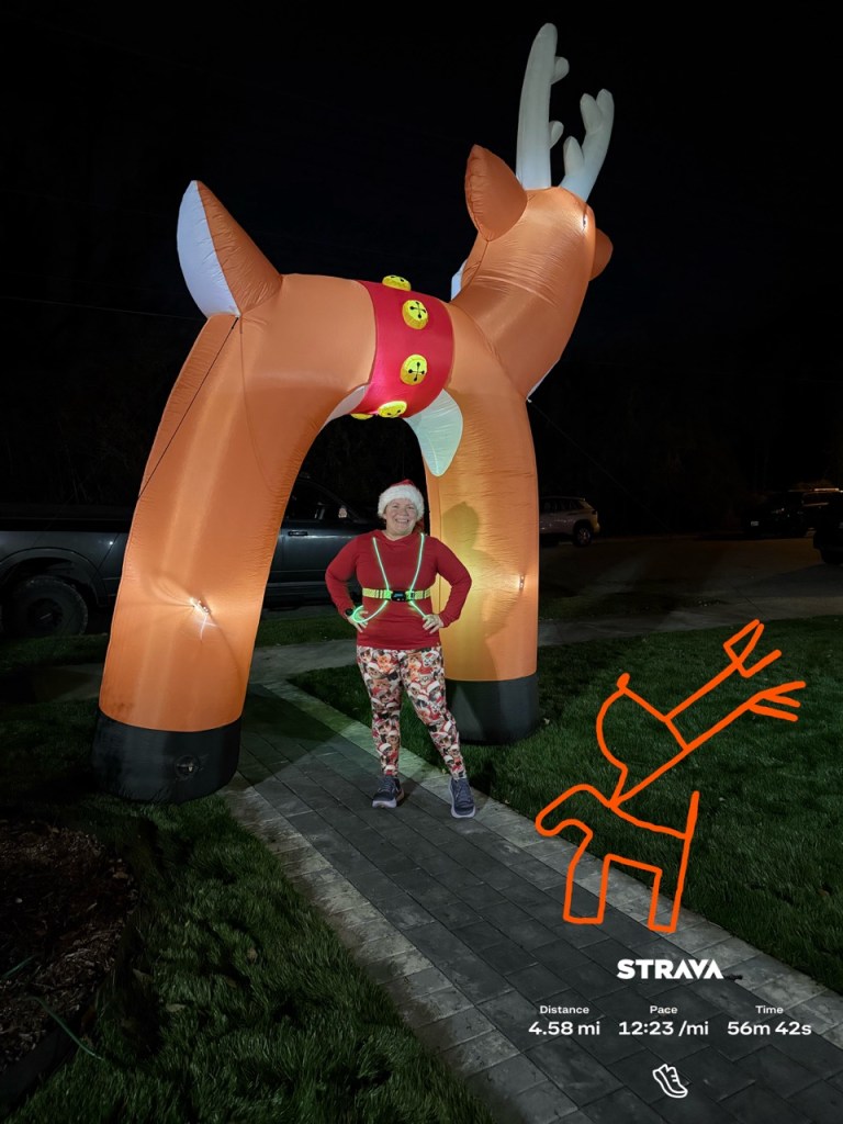 Vanessa Junkin posing by an inflatable reindeer arch. The photo also shows a Strava map of a reindeer-shaped course. 