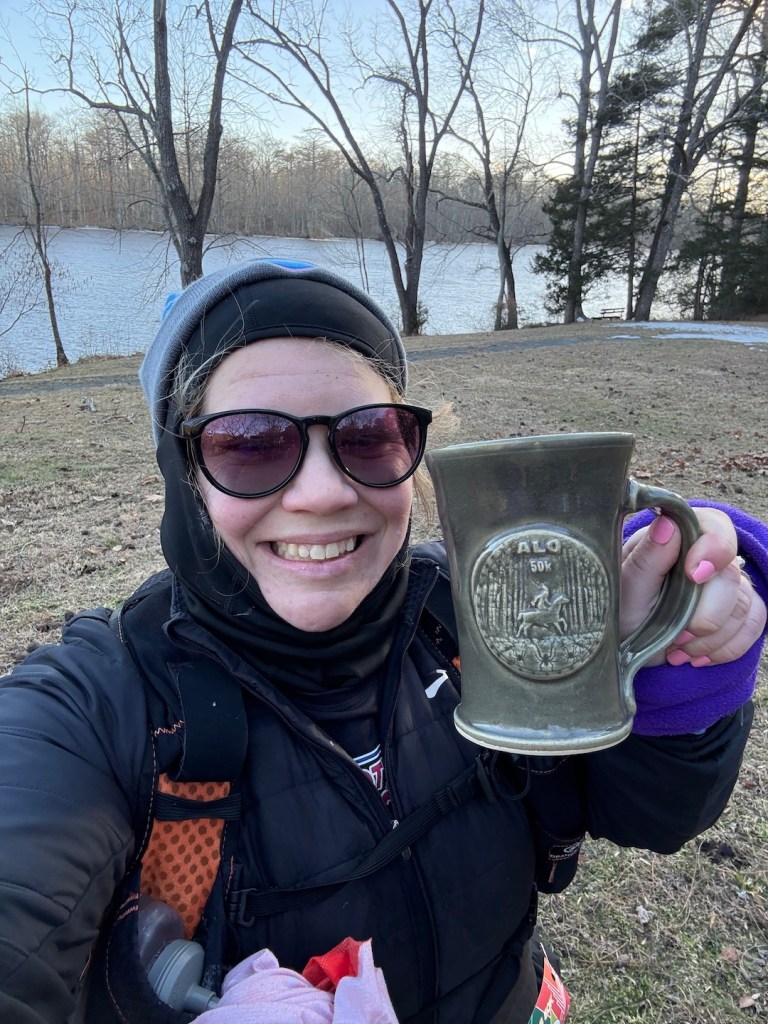 Selfie of smiling runner holding green ALQ 50K mug.