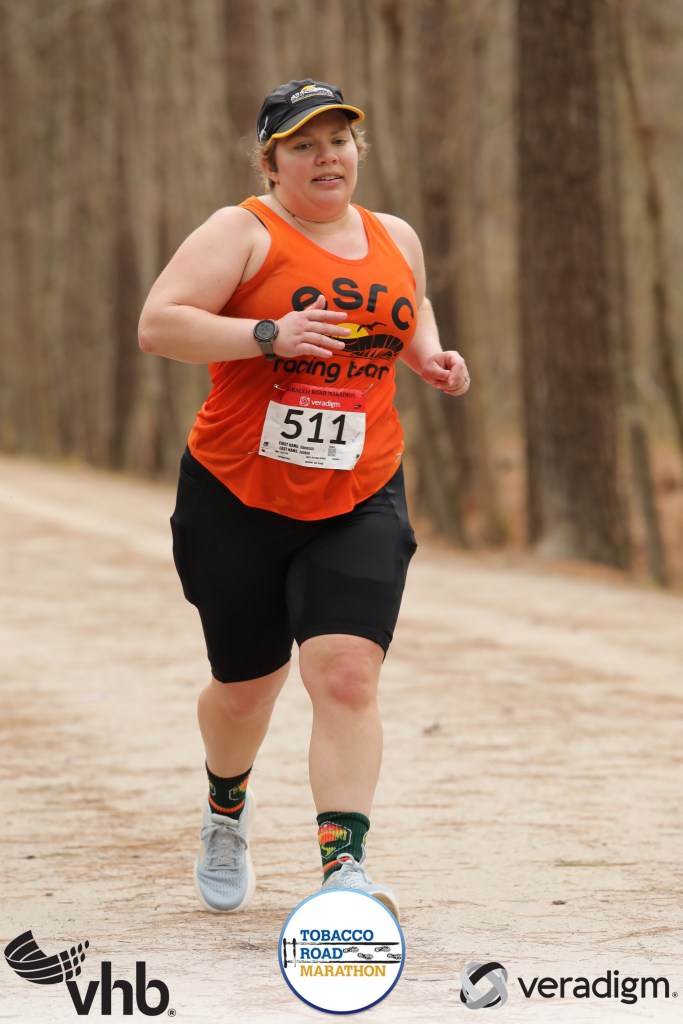 Female runner looking tired on a trail with three miles to go in a marathon. 