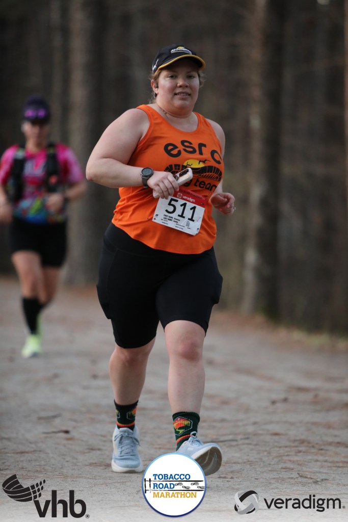 Female runner running on trail, holding phone