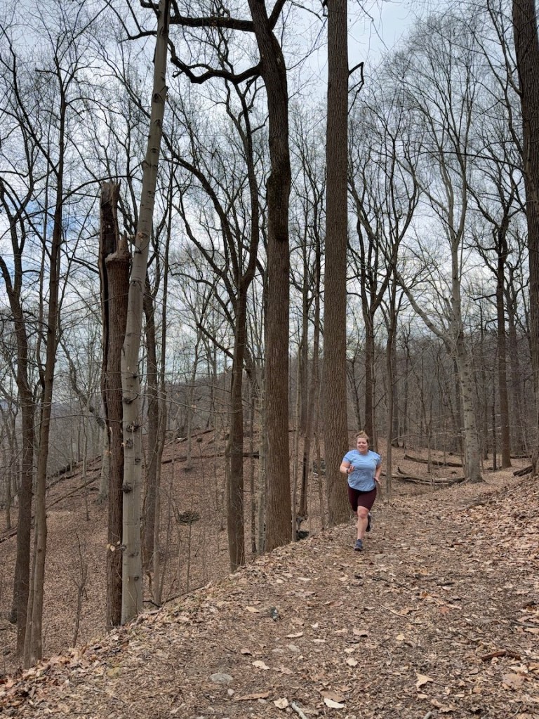 Female runner running on woodsy trail.
