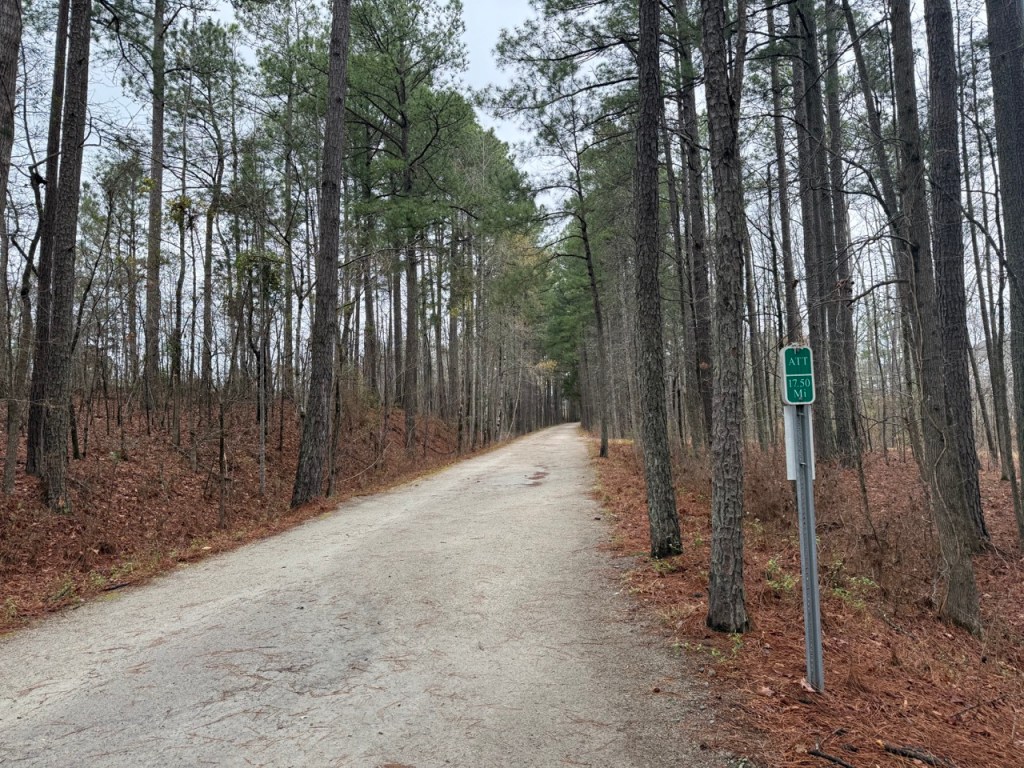 Crushed stone trail with trees on both sides and a small green sign that says "ATT 17.50 Mi."