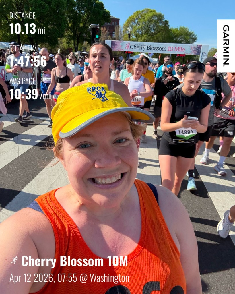 Selfie of a runner smiling after crossing the finish line, with text on the photo: Distance 10.13 mi, Total Time 1:47:56, Avg Pace 10:39/mi, Cherry Blossom 10M Apr 12, 2026 7:55 @ Washington