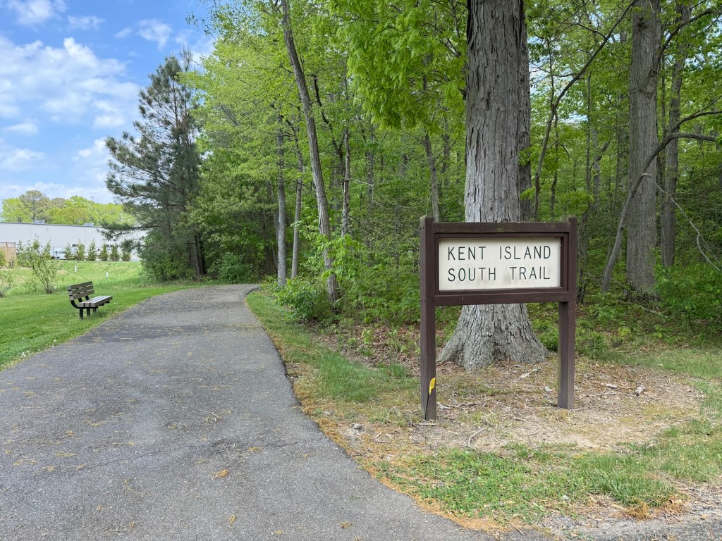 A paved trail showing trees ahead and a sign that reads "Kent Island South Trail."