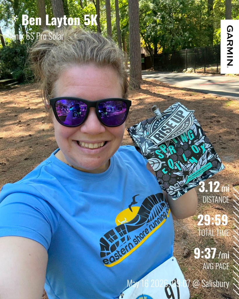 Selfie of female runner holding a bag of coffee. Text reads Ben Layton 5K, fenix 6S Pro Solar, 3.12 mi distance, 29:59 total time, 9:37/mi avg pace, May 16 2026 09:07 @ Salisbury.