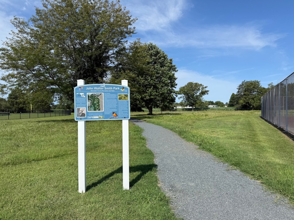 Sign for the walking trail at John Walter Smith Park, shown next to the path.